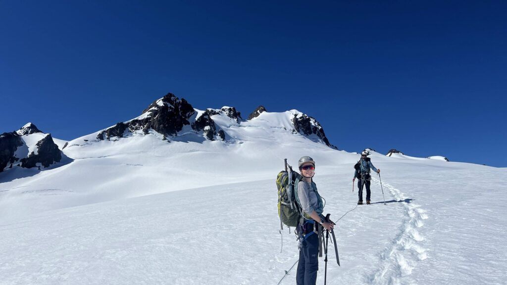Two climbers grossing the Blue Glacier with Mount Olympus in the background